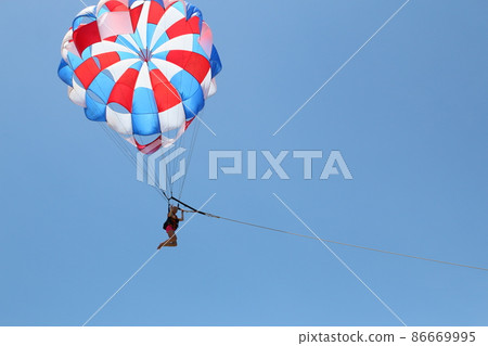 A woman is gliding using a parachute on the background of cloudy blue sky. A woman is gliding using a parachute on the background of cloudy blue sky. 86669995