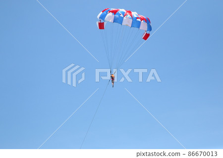 A woman is gliding using a parachute on the background of cloudy blue sky. A woman is gliding using a parachute on the background of cloudy blue sky. 86670013