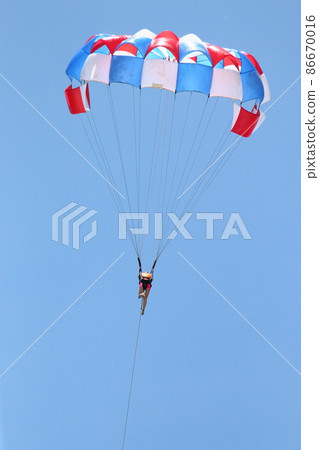 A woman is gliding using a parachute on the background of cloudy blue sky. 86670016