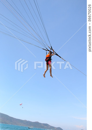 A woman is gliding using a parachute on the background of cloudy blue sky. A woman is gliding using a parachute on the background of cloudy blue sky. 86670026