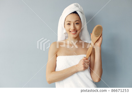 Beautiful girl standing in a studio with massage brush Beautiful girl standing in a studio with massage brush 86671253