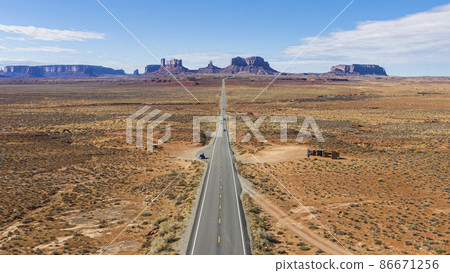 Aerial view of straight steet going towards the spectacular stone towers of Monument Valley in winter Aerial view of straight steet going towards the spectacular stone towers of Monument Valley in winter 86671256