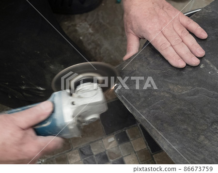 worker cuts ceramic tile with disc grinder close 86673759