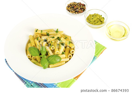 Penne pasta with spinach basil pesto sauce on white plate. Penne pasta with spinach basil pesto sauce on white plate. 86674393
