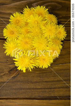 Fresh yellow dandelions in wooden bowl, top view. 86674606