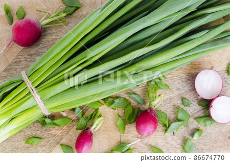 Fresh green onions, red radish on cutting board. Fresh green onions, red radish on cutting board. 86674770