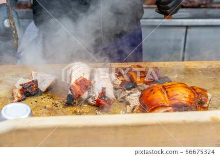 Street grill, fried meat. A man cuts a fried piece of meat into portion. Traditional christmas street food fair in Monaco. Street grill, fried meat. A man cuts a fried piece of meat into portion. Traditional christmas street food fair in Monaco. 86675324