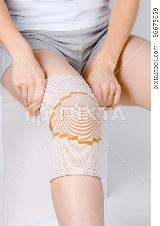 Knee Support Brace on leg isolated on white background. Elastic orthopedic orthosis. Anatomic braces for knee fixation, injuries and pain. Protective knee joint bandage sleeve. Trauma, rehabilitation. 86675659