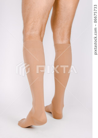 Medical Compression Stockings for varicose veins and venouse therapy. Compression Hosiery. Sock for sports isolated on white background. Beige color socks mock up for advertising, branding, design. 86675733