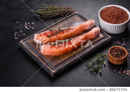 Fresh salmon fillets on black cutting board with herbs and spices Fresh salmon fillets on black cutting board with herbs and spices 86675794