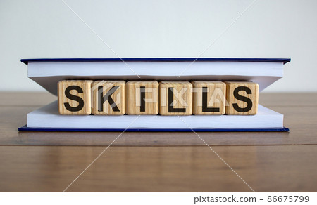Concept word 'skills' on wooden circles between pages of a book on a beautiful wooden table. White background. Business concept. 86675799