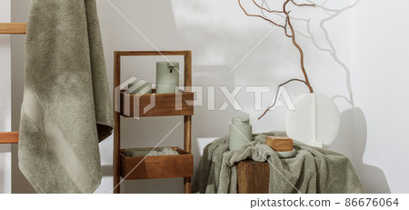 Modern aesthetic bathroom accessories in eucalyptus light green shade. Organic cotton bath towels, minimalistic Scandinavian style vase, sensor soap and lotion dispenser on solid oak stump. Daily Modern aesthetic bathroom accessories in eucalyptus light green shade. Organic cotton bath towels, minimalistic Scandinavian style vase, sensor soap and lotion dispenser on solid oak stump. Daily 86676064