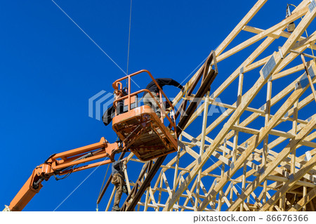 Construction carpenter roofer worker nailing wood beams with hammer on roof installation 86676366