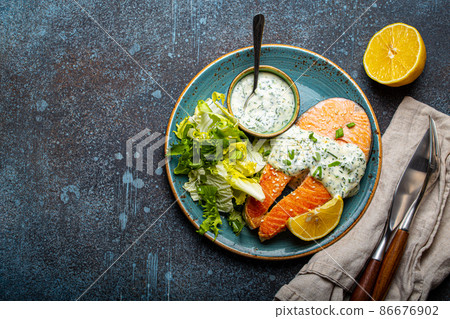 Healthy food meal cooked grilled salmon steaks with dill sauce and salad leafs on plate Healthy food meal cooked grilled salmon steaks with dill sauce and salad leafs on plate 86676902
