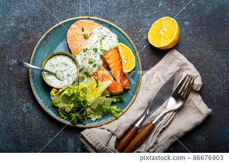 Healthy food meal cooked grilled salmon steaks with dill sauce and salad leafs on plate Healthy food meal cooked grilled salmon steaks with dill sauce and salad leafs on plate 86676903