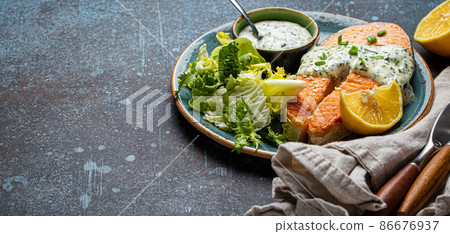 Healthy food meal cooked grilled salmon steak with white dill sauce and green salad leafs Healthy food meal cooked grilled salmon steak with white dill sauce and green salad leafs 86676937