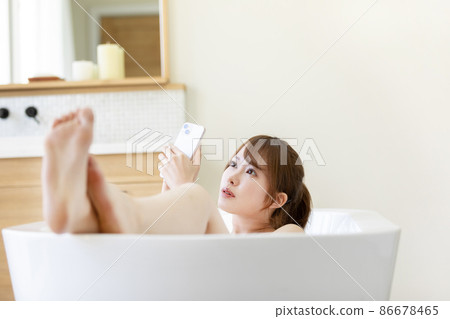 A woman using a smartphone in a bath A woman using a smartphone in a bath 86678465