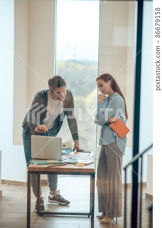 Man pointing at laptop screen to attentive woman Man pointing at laptop screen to attentive woman 86679158