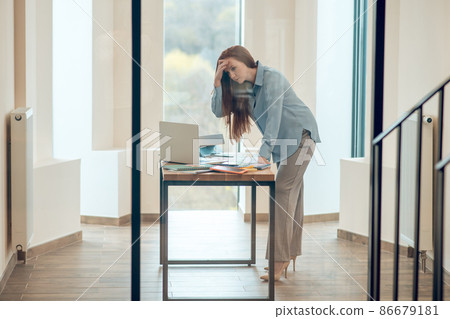 Working mother standing from desk and noticing a small bladder leak