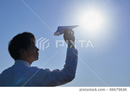 Silhouette of a man flying a paper plane 86679686