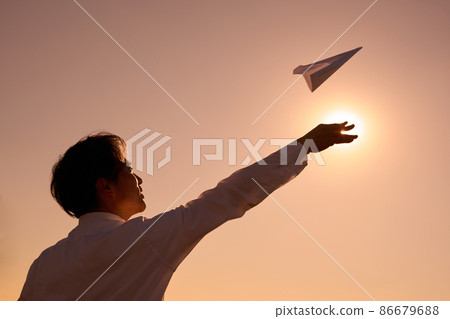 Silhouette of a man flying a paper plane 86679688