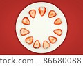 Top view of half strawberry in a plate on isolated red background. 86680088