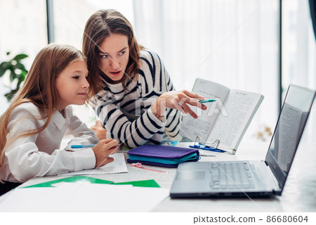 Mother and daughter watching a textbook together. Mother and daughter watching a textbook together. 86680604