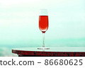 Red champagne glass and copy space that blends into the light blue landscape 86680625