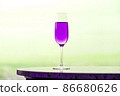 Pink-purple champagne glass and copy space that blends into the yellow-green landscape 86680626