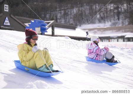Elementary school girl playing in the snow on the ski slopes 86680853