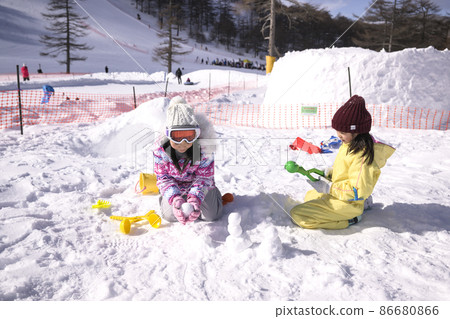 Elementary school girl playing in the snow on the ski slopes Elementary school girl playing in the snow on the ski slopes 86680866