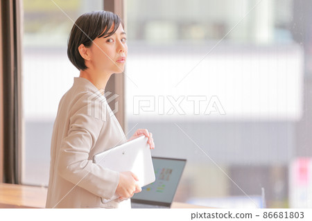 A business woman with an uneasy expression looking back at her tablet 1 86681803