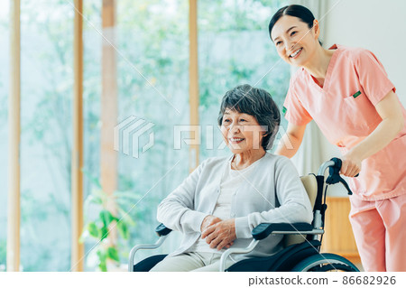 A senior woman in a wheelchair and a middle-aged woman caring for her A senior woman in a wheelchair and a middle-aged woman caring for her 86682926
