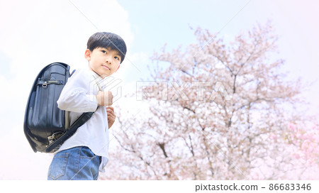 Elementary school boy standing in front of a cherry tree Elementary school boy standing in front of a cherry tree 86683346