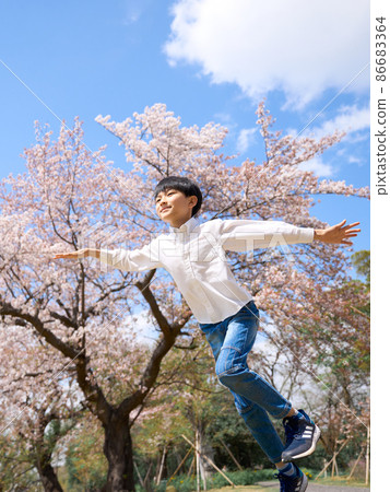 一個男孩在櫻桃樹前張開雙臂奔跑 86683364