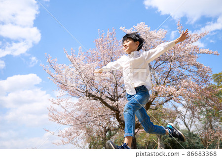 一個男孩在櫻桃樹前張開雙臂奔跑 86683368