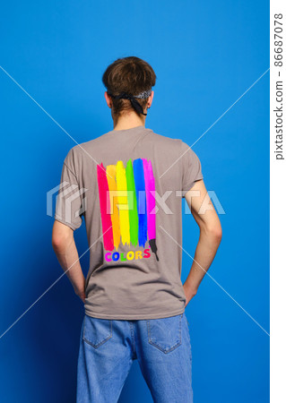 Back view of young man in t-shirt with lgbtq flag on blue background Back view of young man in t-shirt with lgbtq flag on blue background 86687078