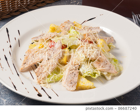 tasty Caesar salad with chicken on a white plate tasty Caesar salad with chicken on a white plate 86687240