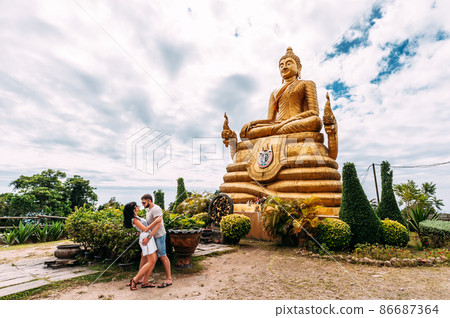 A couple in love travels around Asia. Guy and girl in Thailand. Travelers near the Buddha statue. Big Buddha. Golden Buddha. Man and woman traveling. Couple on a tour. Wedding travel 86687364