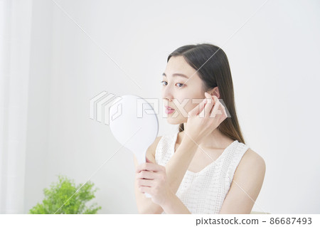 A woman looking at her hair in the mirror 86687493