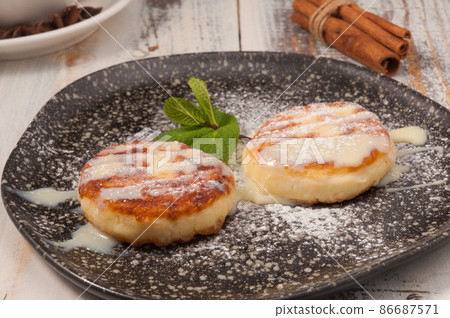 cheesecakes with condensed milk and a mint leaf on a dark plate 86687571