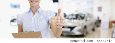 Car sales manager holds thumbs up in car dealership 86687612