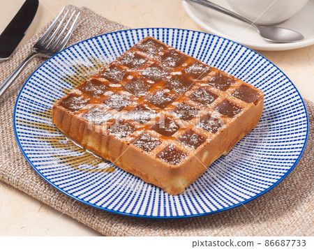 Belgian waffle with caramel with a Cup of tea or coffee. Concept Belgian waffle with caramel with a Cup of tea or coffee. Concept 86687733
