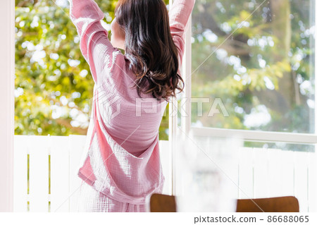 A refreshing woman standing by the window and bathing in the morning light 86688065