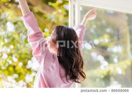 A refreshing woman standing by the window and bathing in the morning light 86688066
