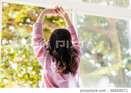 A refreshing woman standing by the window and bathing in the morning light A refreshing woman standing by the window and bathing in the morning light 86688071