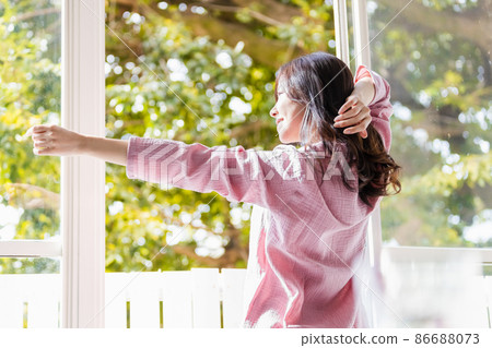 A refreshing woman standing by the window and bathing in the morning light 86688073