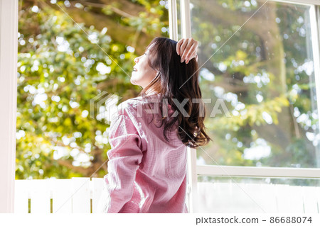 A refreshing woman standing by the window and bathing in the morning light A refreshing woman standing by the window and bathing in the morning light 86688074