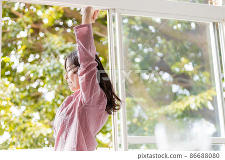 A refreshing woman standing by the window and bathing in the morning light 86688080