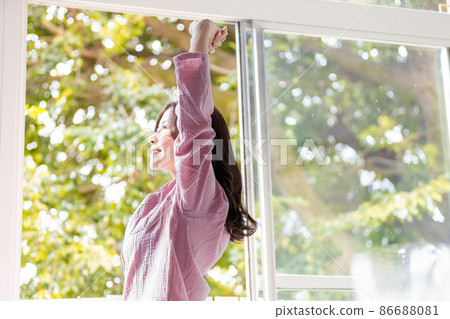 一個清爽的女人站在窗邊沐浴晨光 86688081